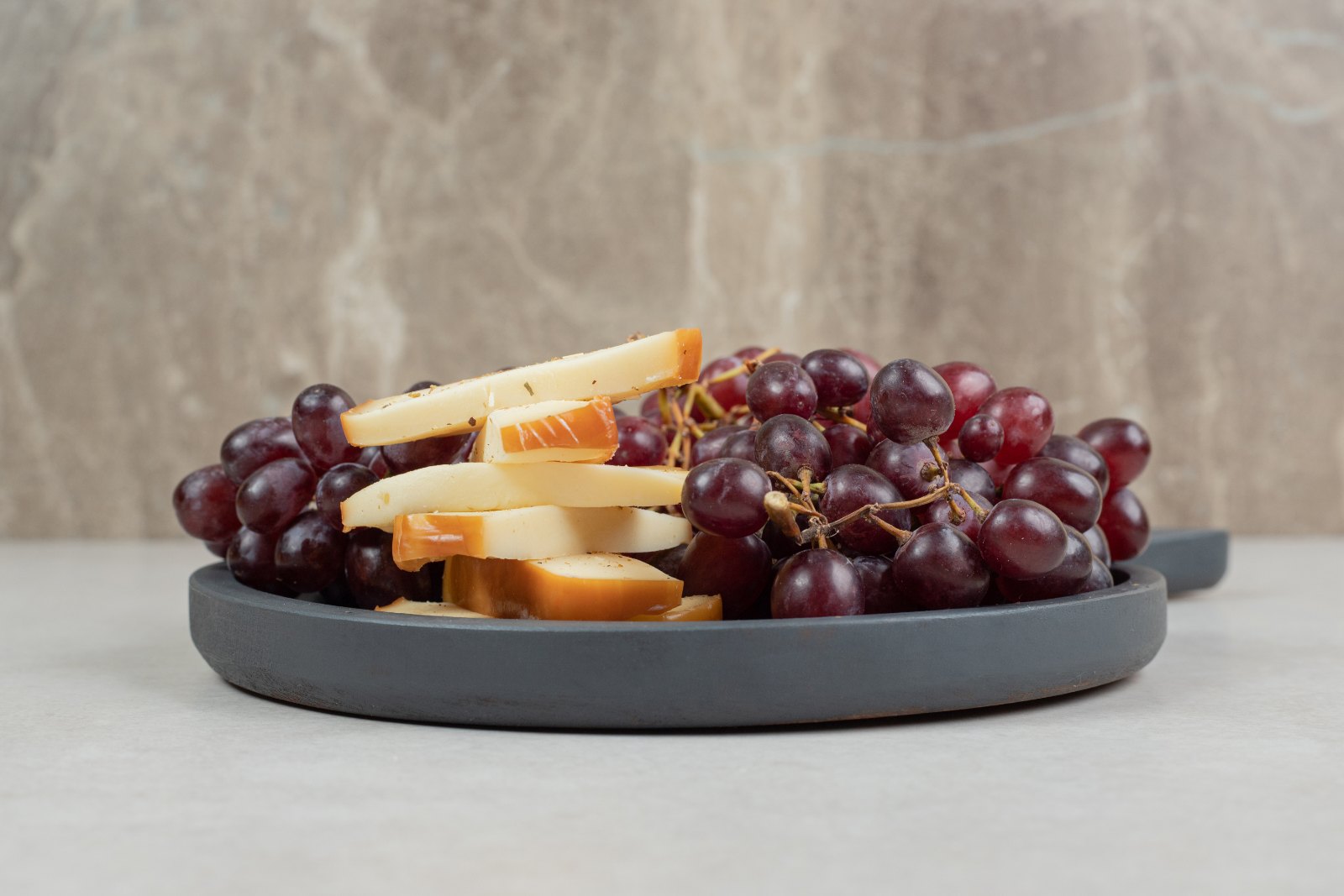 Raisins frais et tranches de fromage sur une planche, goûter simple pour enfant