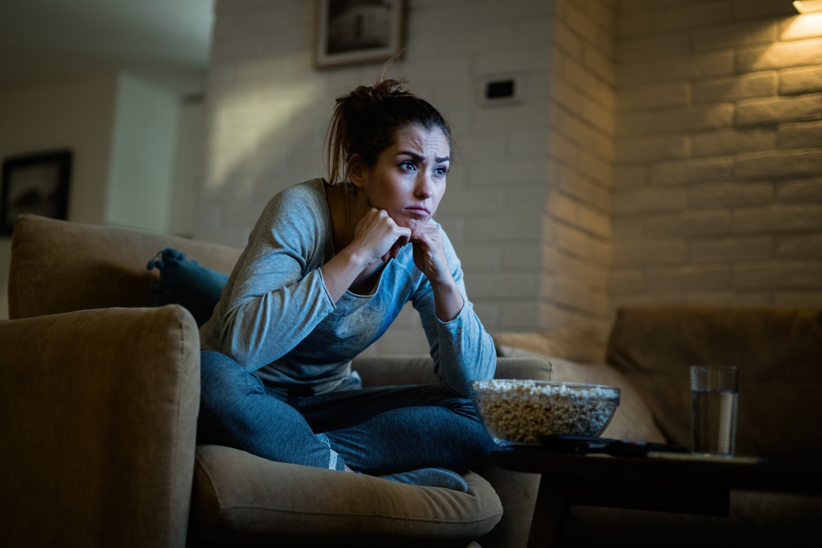 Femme pensive devant la télévision le soir, bol de pop-corn à portée de main : la fringale émotionnelle