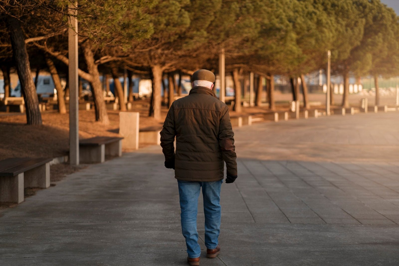 Homme marchant sur une promenade bordée de pins : la marche quotidienne demandée par la dixième règle