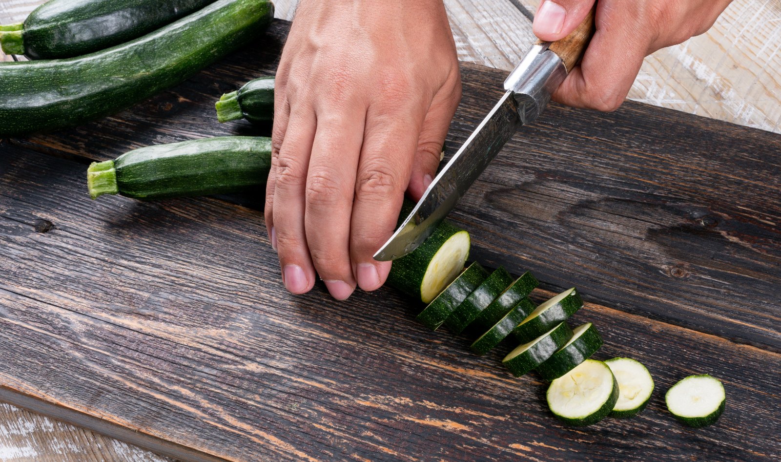 Découpe de courgettes sur une planche en bois, première étape de la session