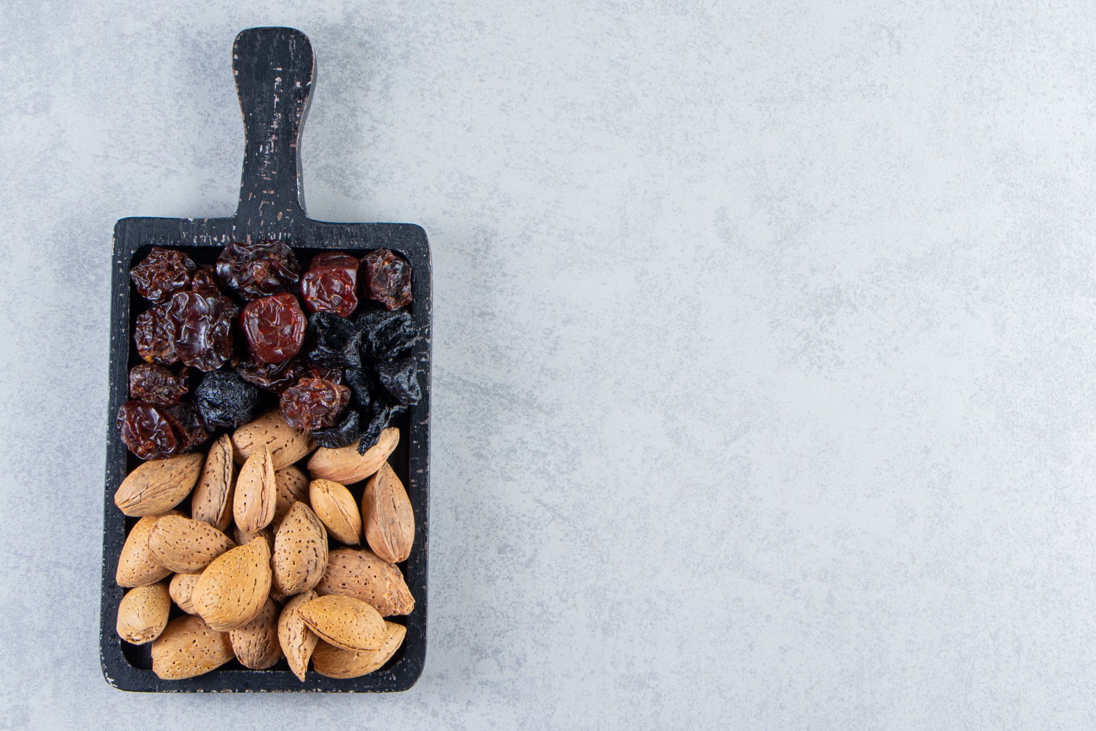 Dattes, fruits séchés et amandes sur une planche : un en-cas facile à emporter