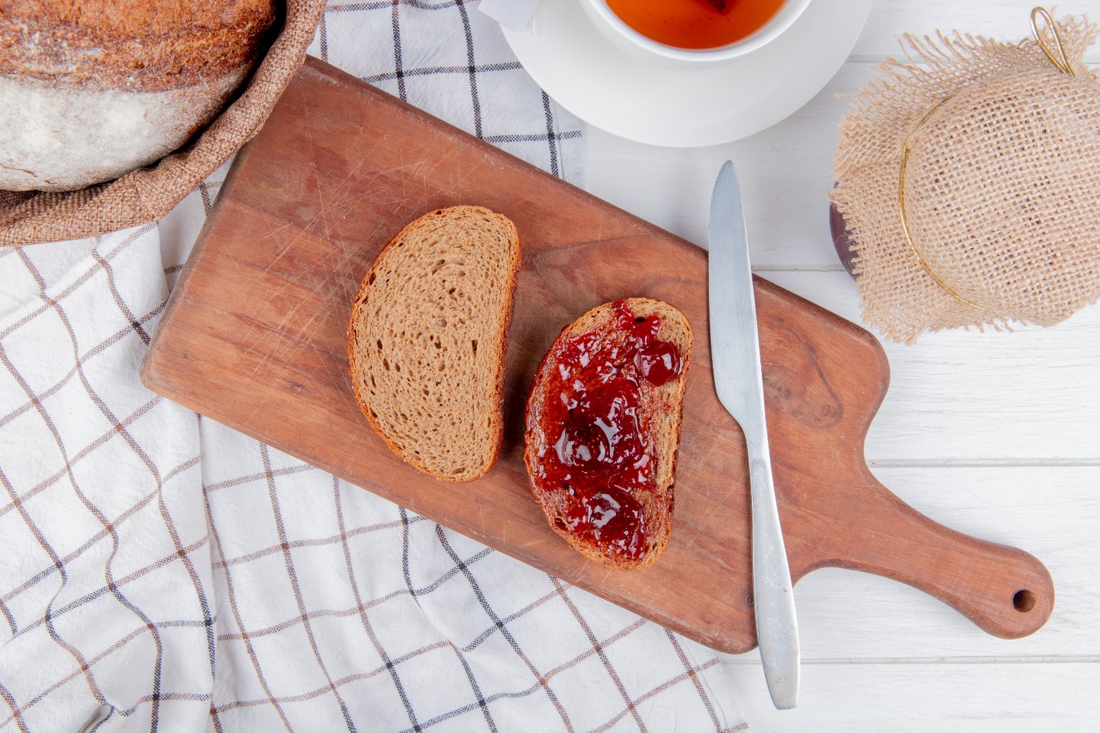 Toast de seigle à la confiture sur une planche, avec une tasse de thé