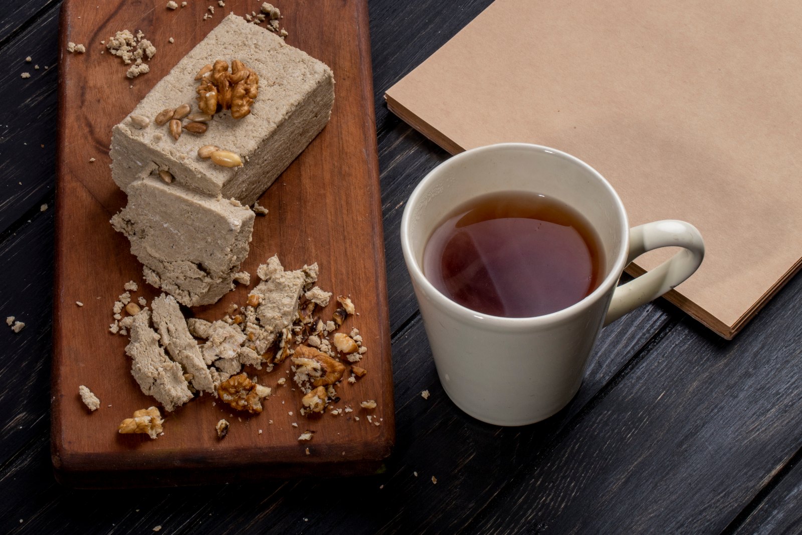 Halva aux graines et aux noix sur une planche en bois, avec une tasse de boisson chaude