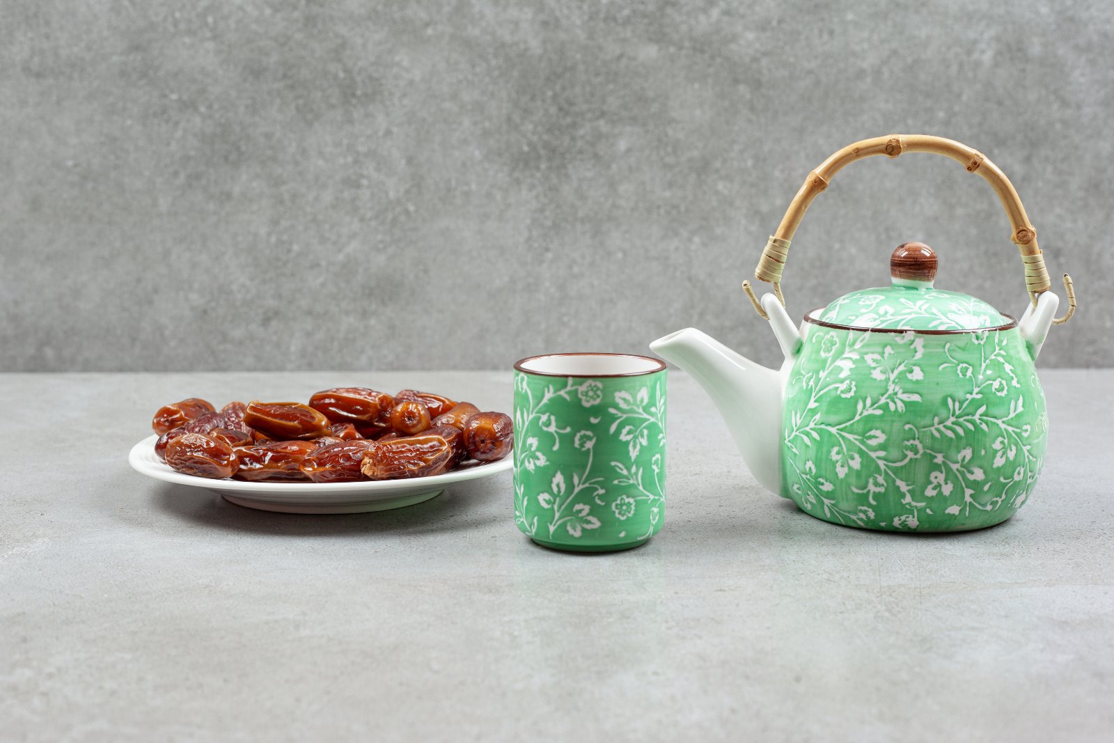 Assiette de dattes avec une théière et une tasse de thé vert