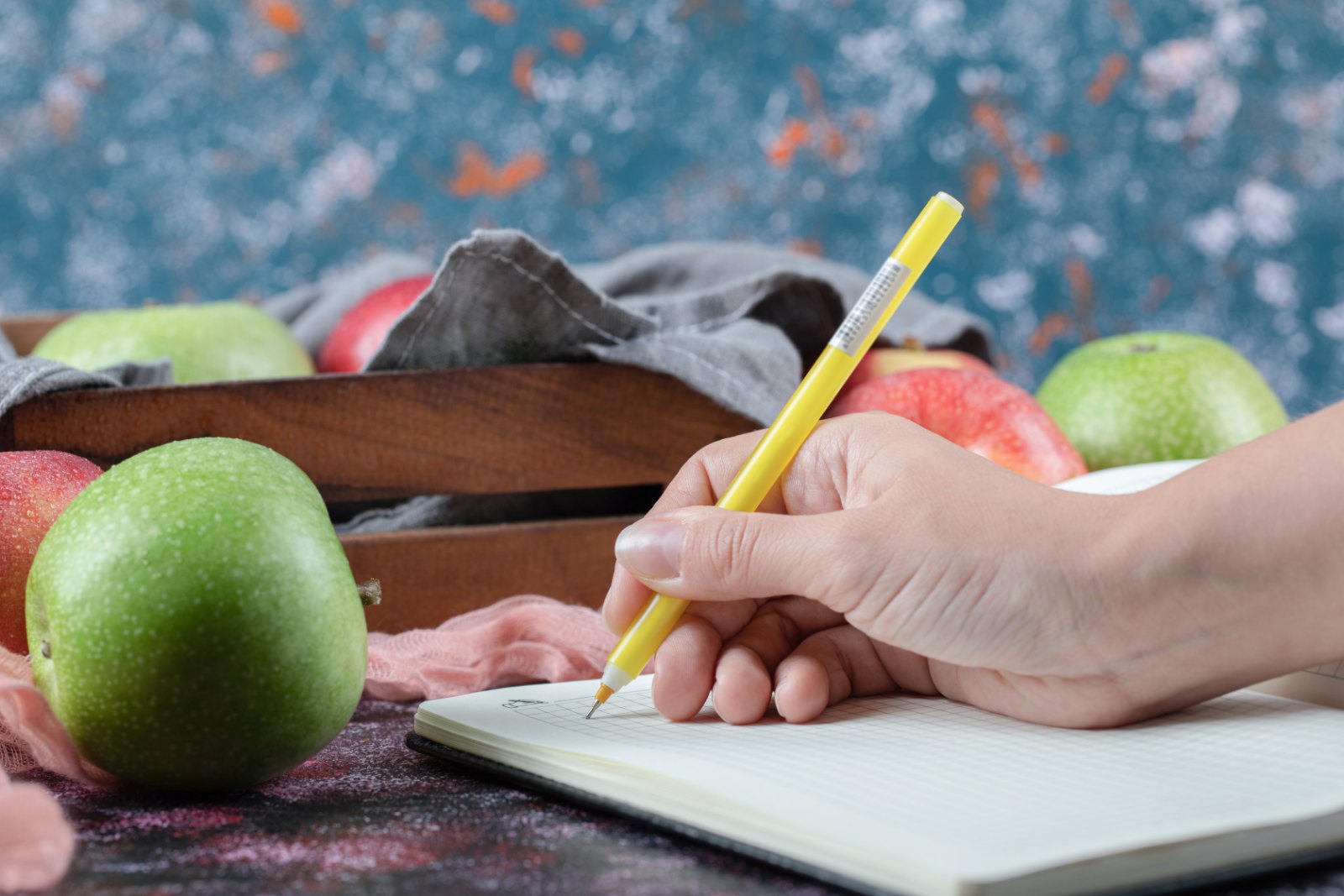 Noter son menu de la semaine dans un carnet, pommes à côté