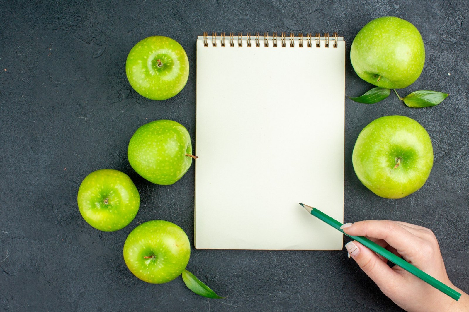 Carnet vierge, crayon et pommes vertes : préparer sa semaine de menus à l’avance