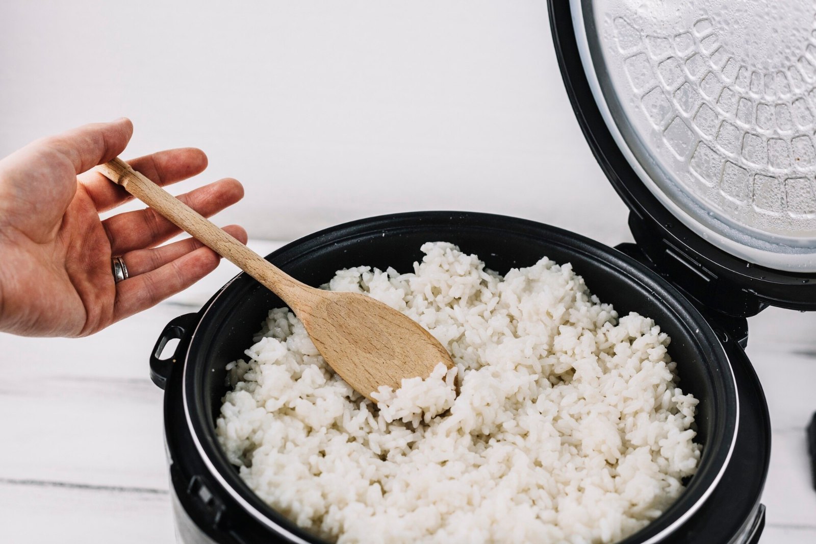 Riz blanc cuit à l’avance dans un cuiseur, servi à la cuillère en bois