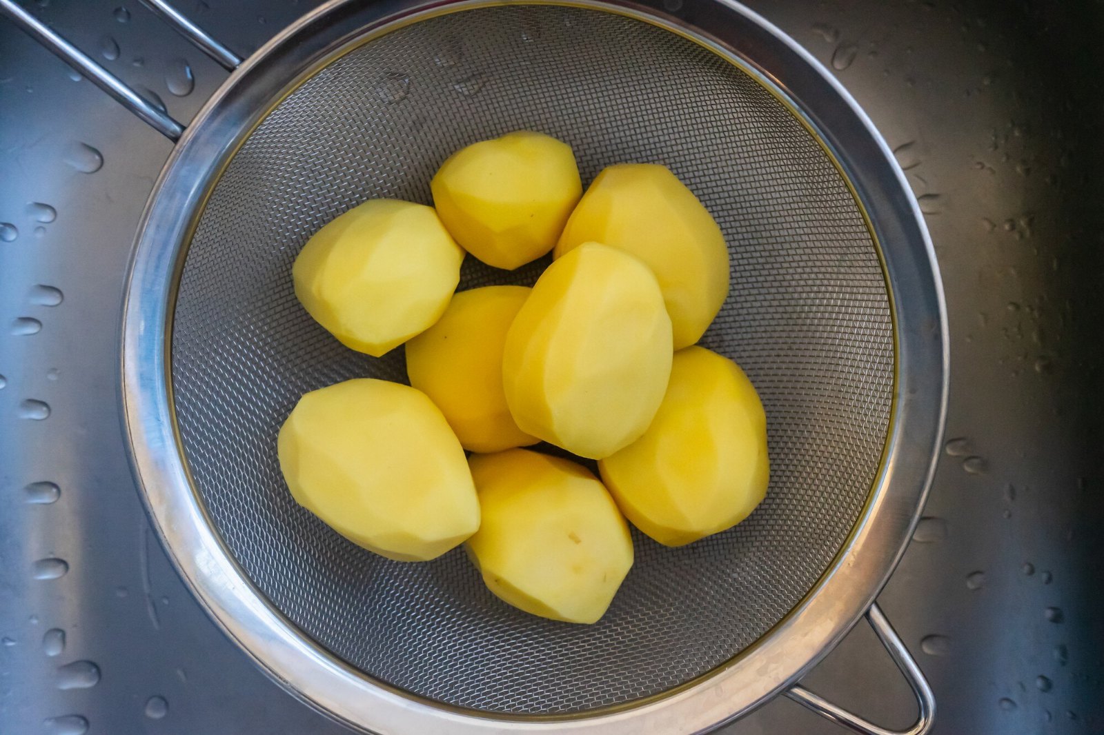 Pommes de terre épluchées dans une passoire, prêtes à bouillir pour la semaine